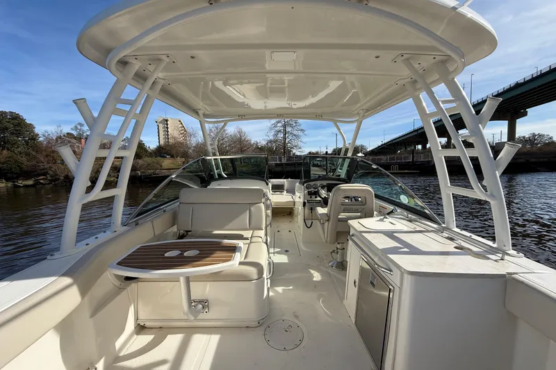 Slide: The Image of 2014 Boston Whaler 270 Vantage boat interior with seating and helm, docked near a bridge. - 12