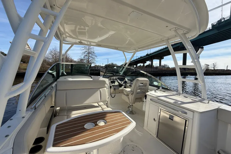 Slide: The Image of 2014 Boston Whaler 270 Vantage boat interior with seating and helm, under a bridge. - 13