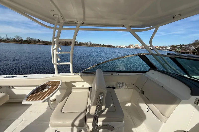 Slide: The Image of 2014 Boston Whaler 270 Vantage boat interior with seating and table, overlooking calm waters. - 19