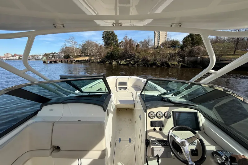 Slide: The Image of 2014 Boston Whaler 270 Vantage boat interior with steering wheel and dashboard, on a scenic river. - 20