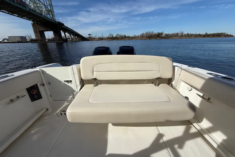 Slide: The Image of 2014 Boston Whaler 270 Vantage boat interior with seating, near a bridge on calm water. - 9