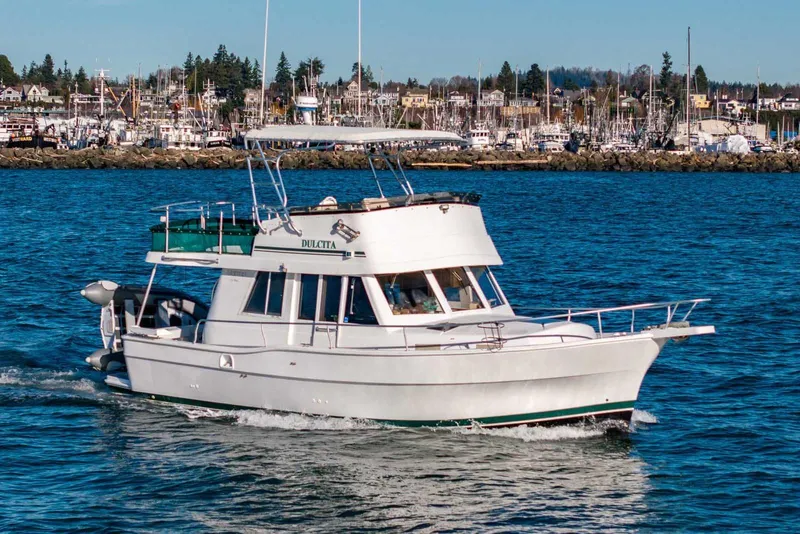 The Image of 1997 Mainship 350 Trawler cruising on blue water near a marina. - 1