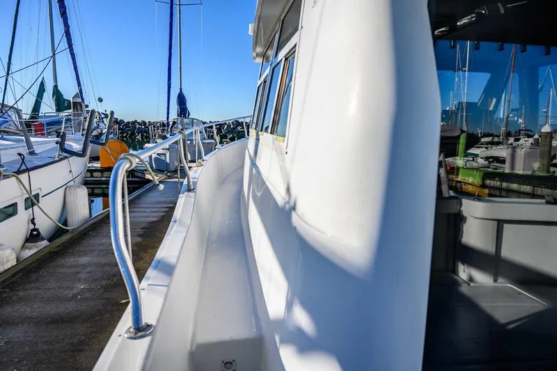 Slide: The Image of 1997 Mainship 350 Trawler docked at marina, side view with clear blue sky. - 14