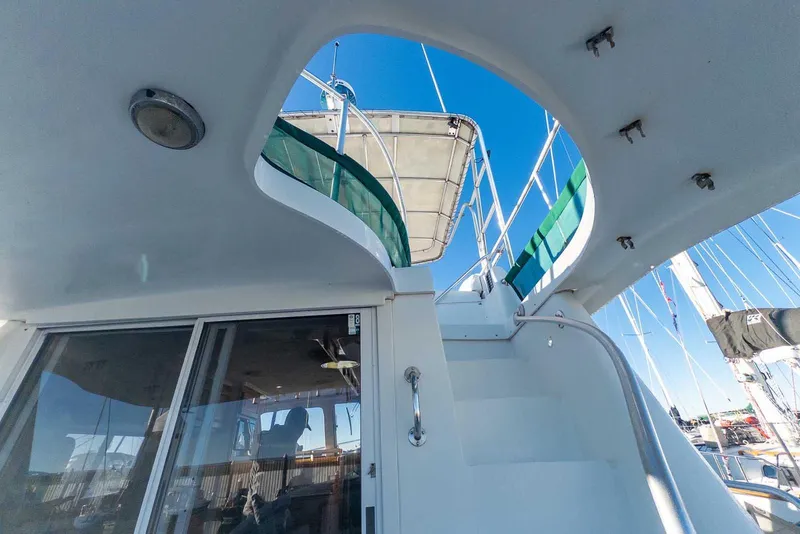 Slide: The Image of 1997 Mainship 350 Trawler, view of stairs and deck under clear blue sky. - 17