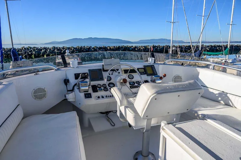 Slide: The Image of 1997 Mainship 350 Trawler helm with navigation equipment, overlooking a scenic marina view. - 18