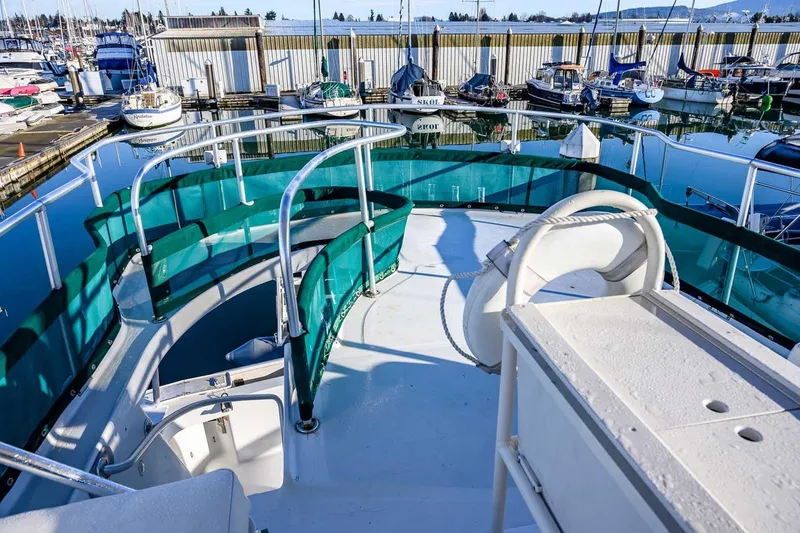 Slide: The Image of 1997 Mainship 350 Trawler deck view at marina, featuring green railings and seating. - 20