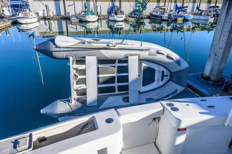 Slide: The Image of 1997 Mainship 350 Trawler docked with inflatable boat, reflecting on calm marina waters. - 23