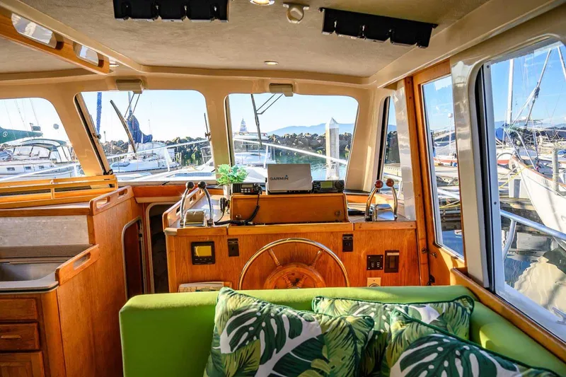 Slide: The Image of Interior of 1997 Mainship 350 Trawler with helm, green sofa, and marina view. - 30
