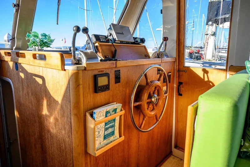 Slide: The Image of 1997 Mainship 350 Trawler helm with wooden wheel, controls, and nautical decor. - 31