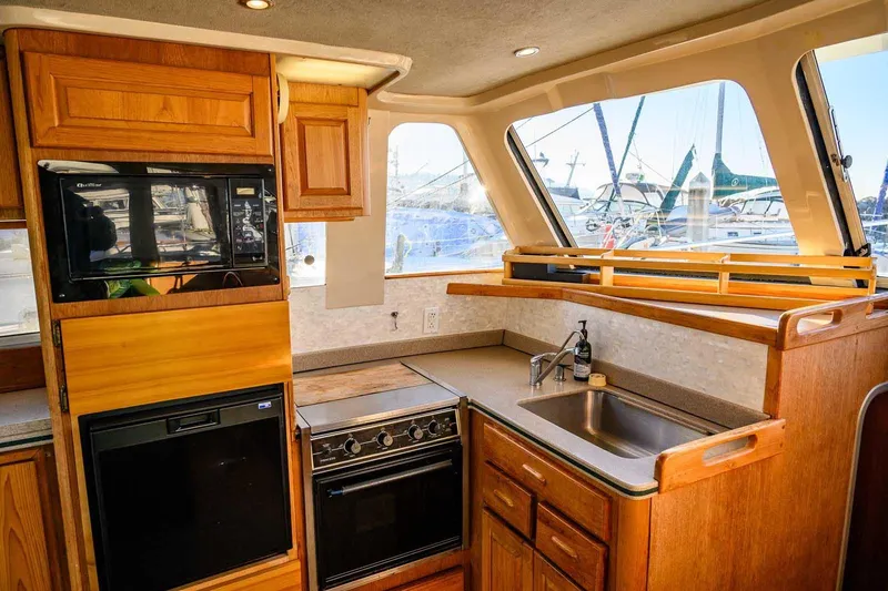 Slide: The Image of 1997 Mainship 350 Trawler kitchen with wood cabinetry, stove, and sink, overlooking marina. - 34