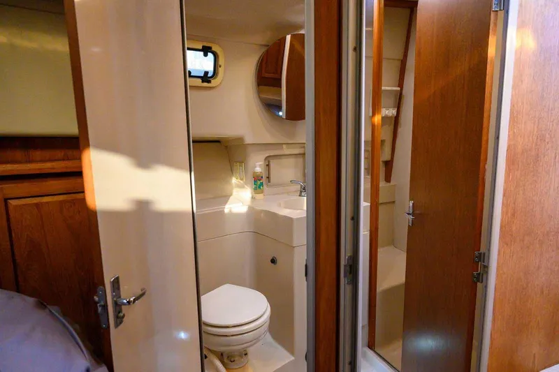 Slide: The Image of 1997 Mainship 350 Trawler bathroom with sink, toilet, and wooden cabinetry. - 42