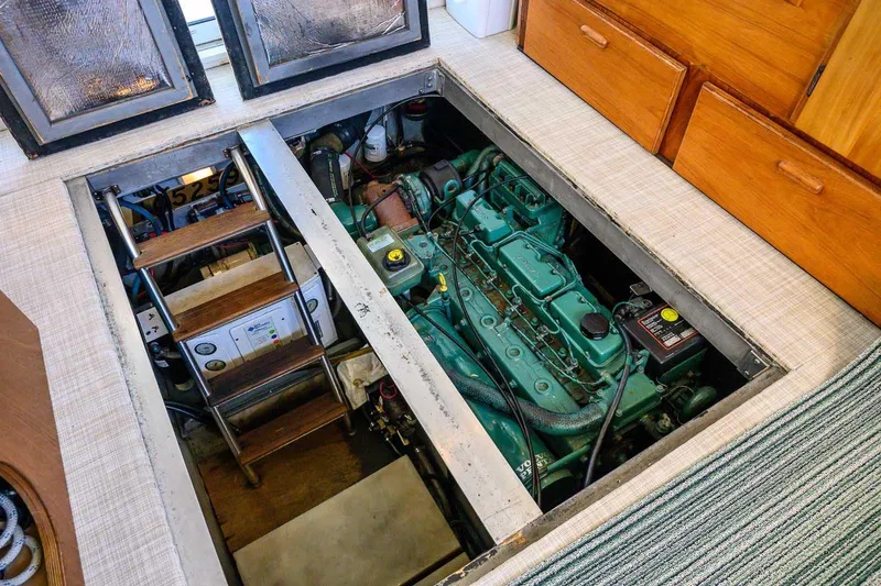 Slide: The Image of Engine room of 1997 Mainship 350 Trawler with visible green engine and wooden steps. - 49