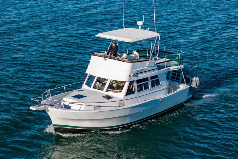 Slide: The Image of 1997 Mainship 350 Trawler cruising on open water, featuring a spacious deck and flybridge. - 55