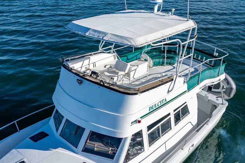 Slide: The Image of 1997 Mainship 350 Trawler cruising on open water, featuring spacious deck and canopy. - 6