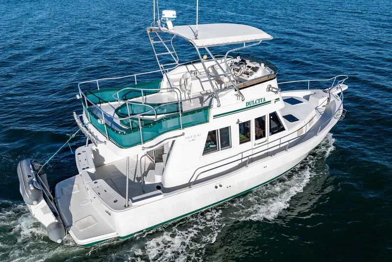 Slide: The Image of 1997 Mainship 350 Trawler cruising on open water, featuring spacious deck and upper helm. - 8