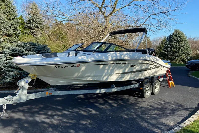The Image of 2016 Sea Ray SPX 210 Outboard boat on trailer, parked in a driveway with trees. - 0