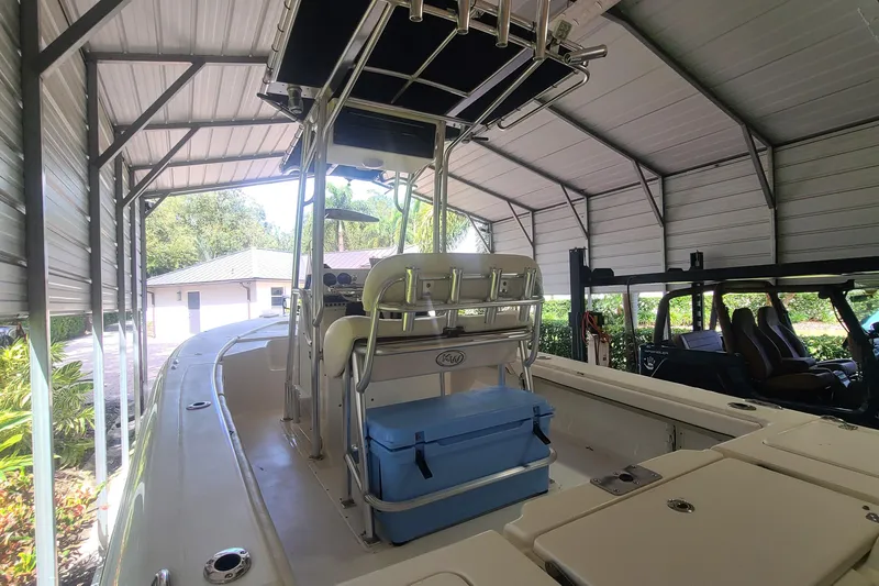 Slide: The Image of 2008 Key West 246 Bay Reef boat under metal shelter, featuring helm and seating. - 21