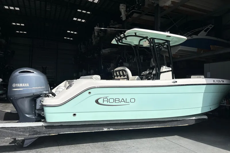 Slide: The Image of 2023 Robalo R242 Center Console boat with twin Yamaha engines in storage facility. - 1