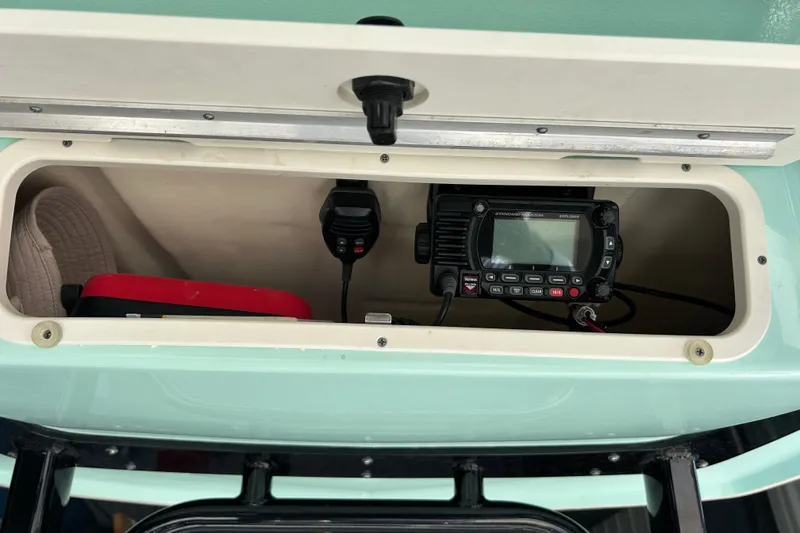Slide: The Image of 2023 Robalo R242 Center Console storage with radio equipment and red case. - 26