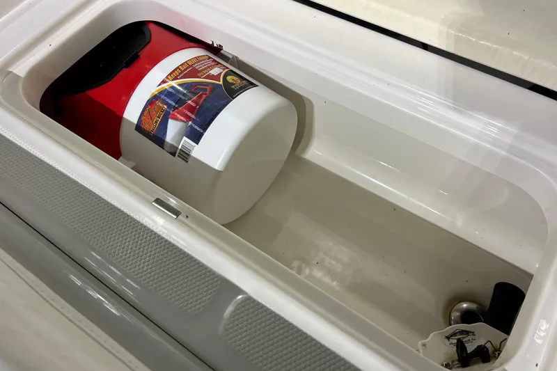 Slide: The Image of 2023 Robalo R242 Center Console storage compartment with a red and white bucket inside. - 31