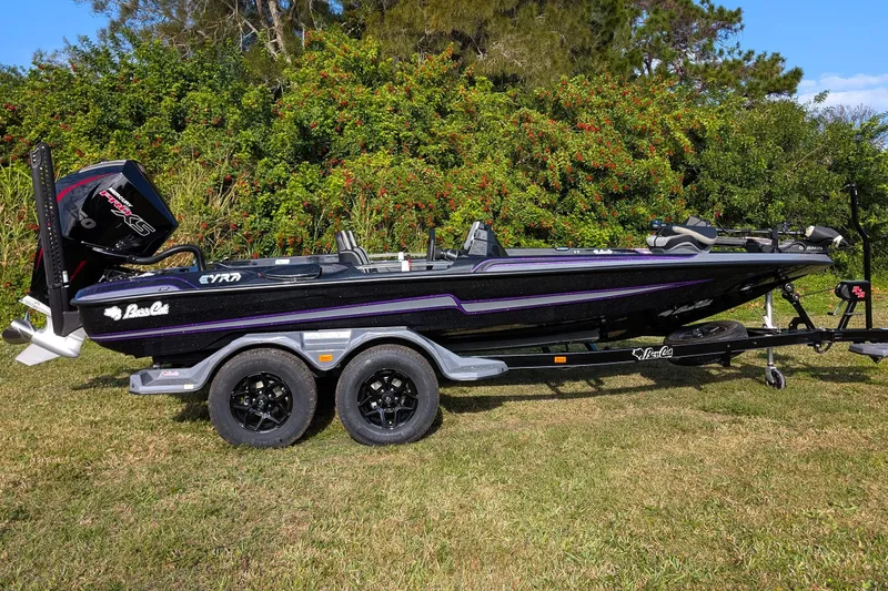 Slide: The Image of 2026 Bass Cat Eyra SP boat on trailer, parked on grass with lush greenery background. - 2