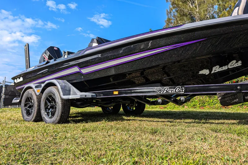 Slide: The Image of 2026 Bass Cat Eyra SP boat on trailer, black with purple accents, parked on grass. - 4