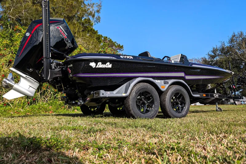 Slide: The Image of 2026 Bass Cat Eyra SP boat on trailer, black with purple accents, parked on grass. - 5