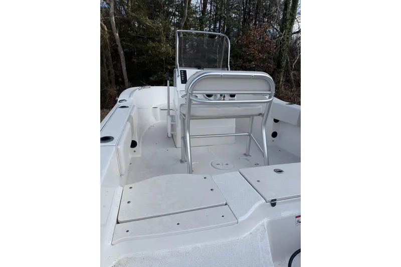 Slide: The Image of 2016 Robalo R180 Center Console boat interior with seating and console, surrounded by trees. - 2