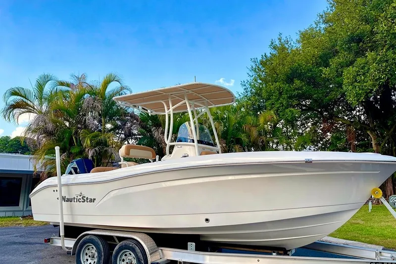 Slide: The Image of 2024 NauticStar 222 Offshore boat on trailer, surrounded by lush greenery. - 3