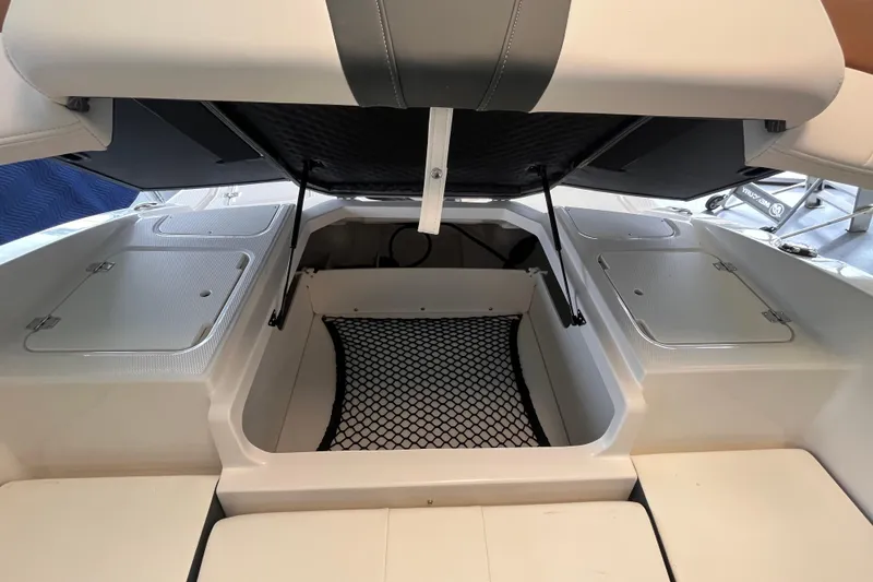 Slide: The Image of 2025 Chaparral 21 SSi OB boat interior storage compartment with open hatch and netting. - 10