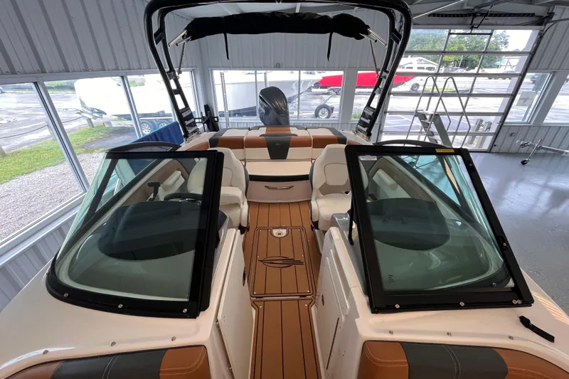 Slide: The Image of 2025 Chaparral 21 SSi OB boat interior with open windshield and seating in a showroom. - 8