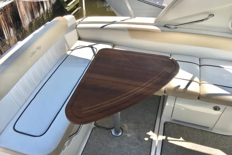 Slide: The Image of 2010 Sea Ray 260 Sundancer interior with wooden table and cushioned seating. - 12