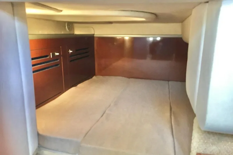 Slide: The Image of 2010 Sea Ray 260 Sundancer cabin interior with cozy bed and wooden cabinetry. - 19