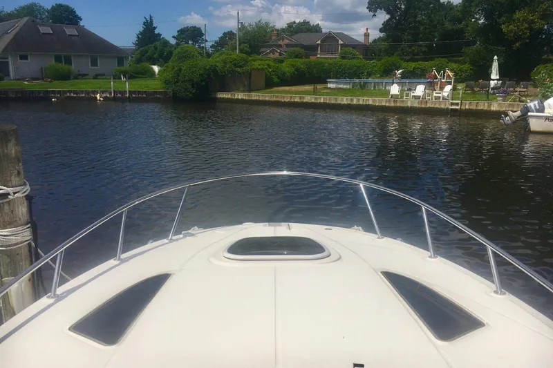 Slide: The Image of Bow view of 2010 Sea Ray 260 Sundancer docked in a serene residential canal. - 4