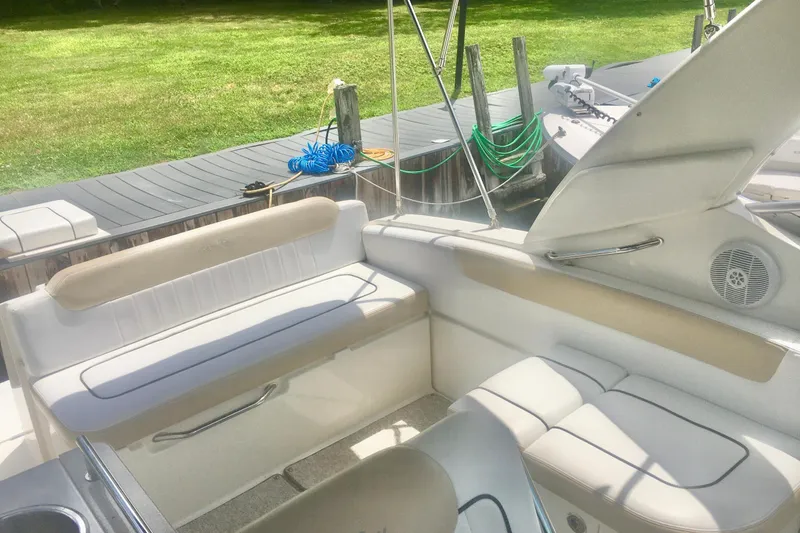 Slide: The Image of 2010 Sea Ray 260 Sundancer boat interior with cushioned seating and dock view. - 8