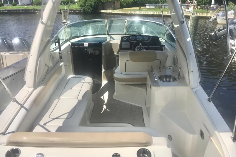 Slide: The Image of 2010 Sea Ray 260 Sundancer boat interior with seating and helm, docked by the water. - 9