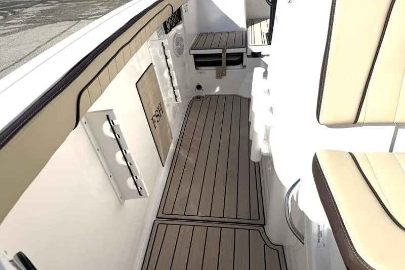 Slide: The Image of 2024 Yamaha Boats 222 FSH Sport interior with beige seating and wood-style flooring. - 25