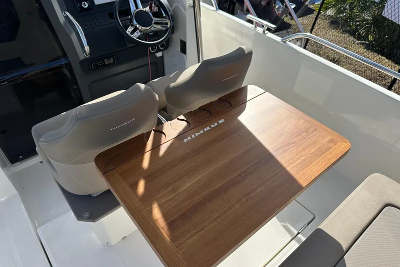 Slide: The Image of 2024 Nimbus T-8 boat interior with wooden table and cushioned seats. - 7
