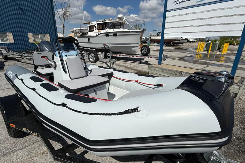 Slide: The Image of 2026 Zodiac Open 4.2 inflatable boat on trailer, marina background, sunny day. - 2