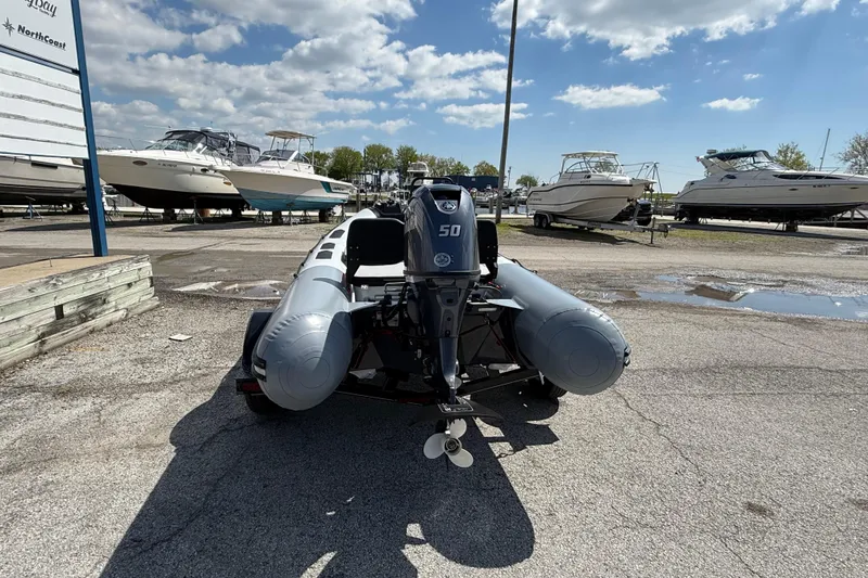Slide: The Image of 2026 Zodiac Open 4.2 inflatable boat with outboard motor in a marina setting. - 4