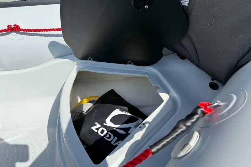 Slide: The Image of Storage compartment of 2026 Zodiac Open 4.2 boat with red rope and black bag. - 6