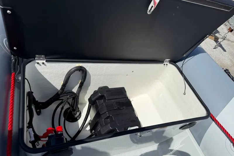 Slide: The Image of Open storage compartment of 2026 Zodiac Open 4.2 boat, featuring battery and wiring. - 7
