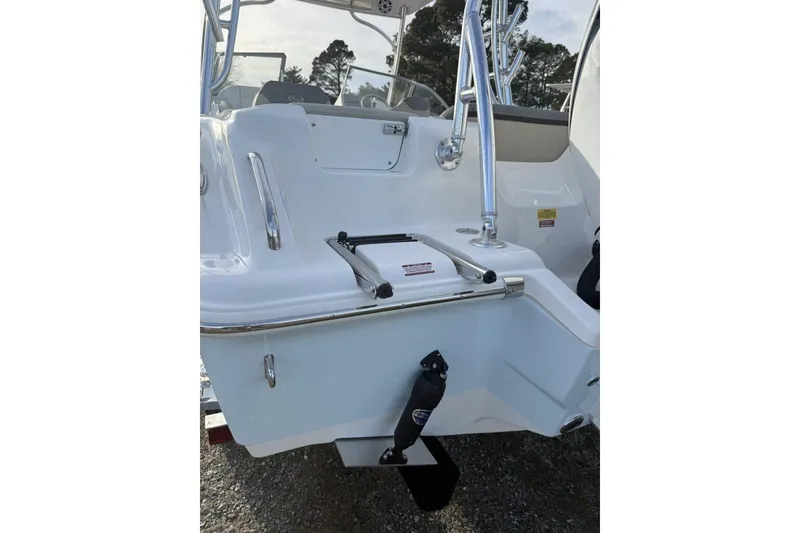 Slide: The Image of 2026 Key West 239 DFS boat stern with ladder and railing, parked on gravel. - 2