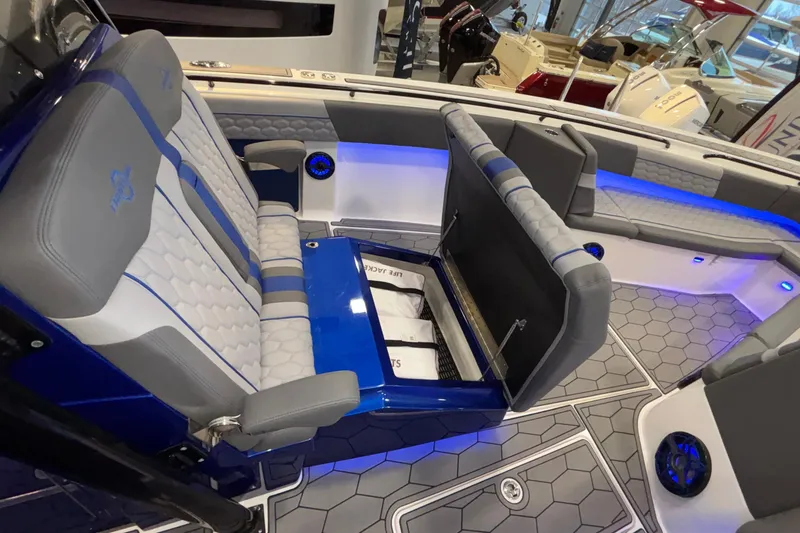 Slide: The Image of 2022 Fountain 38 SC boat interior with gray seating, blue accents, and under-seat storage. - 81