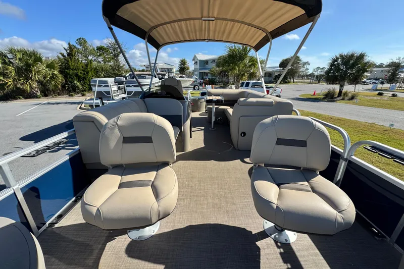 Slide: The Image of 2023 Sun Tracker Fishin' Barge 20 DLX interior with seating and canopy, parked outdoors. - 11