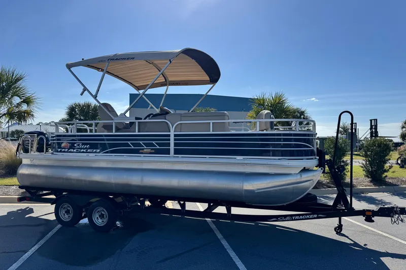 Slide: The Image of 2023 Sun Tracker Fishin' Barge 20 DLX pontoon boat on trailer, sunny day. - 4