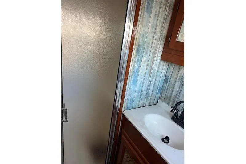 Slide: The Image of 1985 Sunnfjord 40 bathroom with shower, sink, and wood paneling. - 12