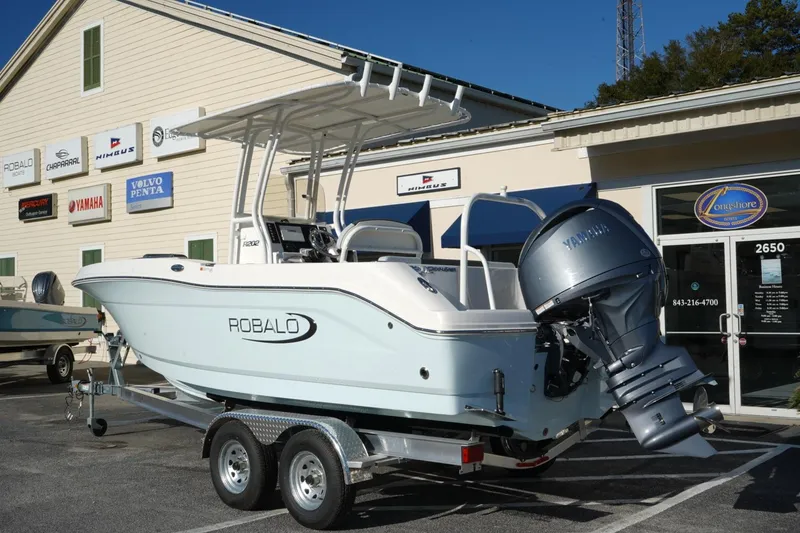 Slide: The Image of 2026 Robalo R202 Explorer boat on trailer, displayed outside dealership. - 2
