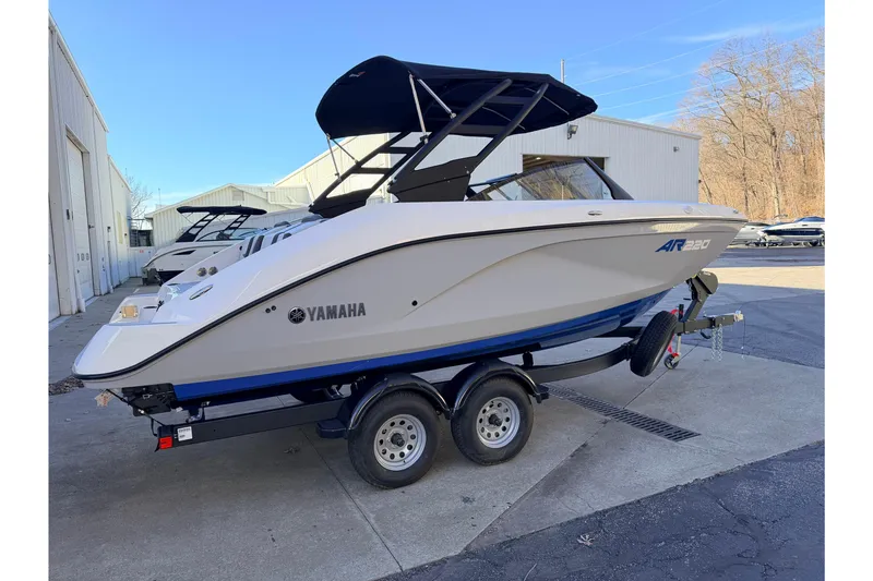Slide: The Image of 2026 Yamaha Boats AR220 on trailer, parked outside a warehouse. - 9