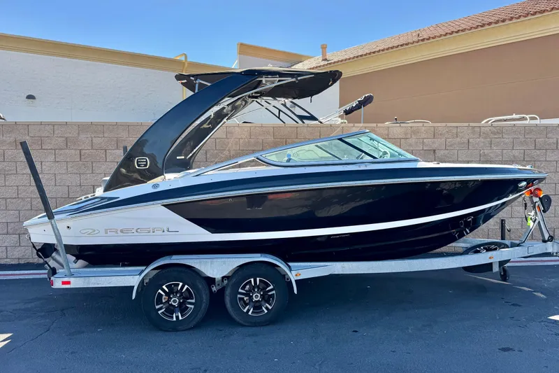 The Image of 2019 Regal 2100 boat on trailer, sleek black and white design. - 0